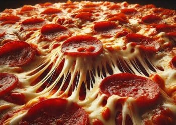 Detailná fotografia horúcej pepperoni pizze s rozťahujúcim sa roztopeným syrom a chrumkavými plátkami salámy.